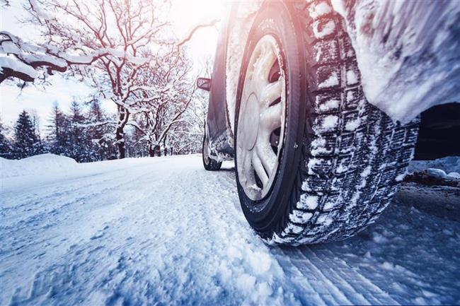 zbliżenie na opony auta jadącego po zaśnieżonej drodze