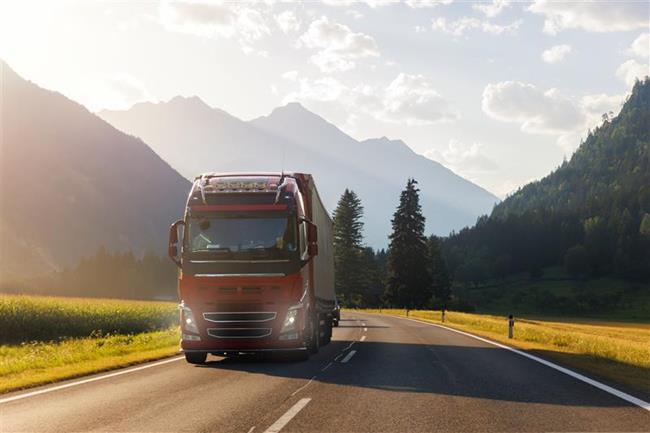 auto ciężarowe jadące drogą po górskich terenach