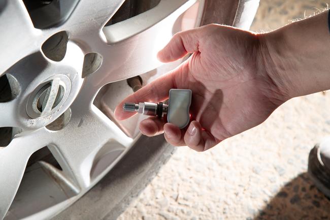 czujnik tpms w ręku na tle koła