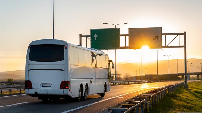 Autokar jadący drogą przy zachodzie słońca.