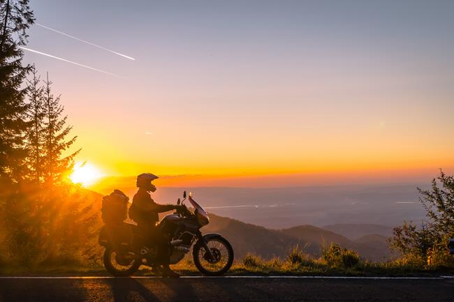 motocyklista w górach na tle zachodzącego słońca