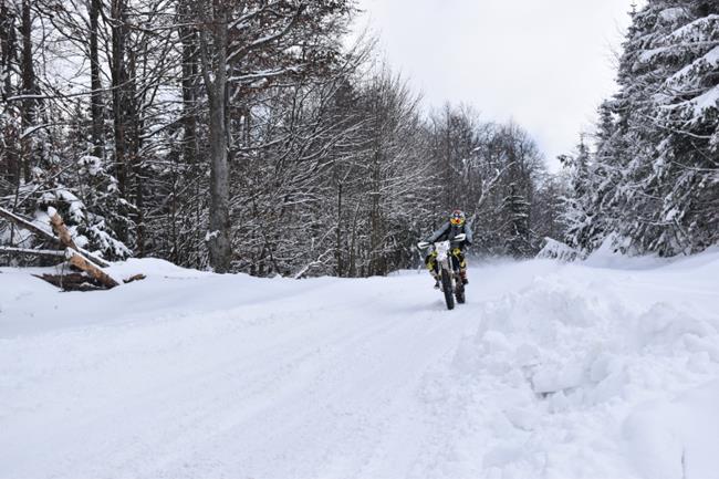 Motocyklista na ośnieżonej, leśnej drodze