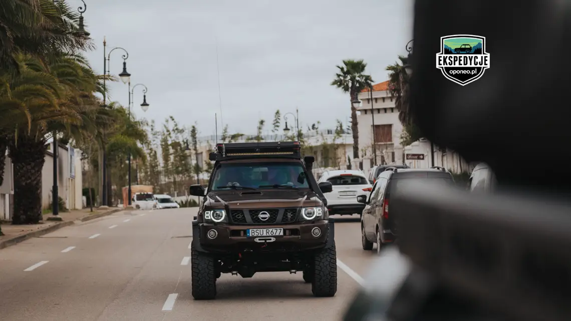 samochód 4x4 jadący po drodze z palamami w tle